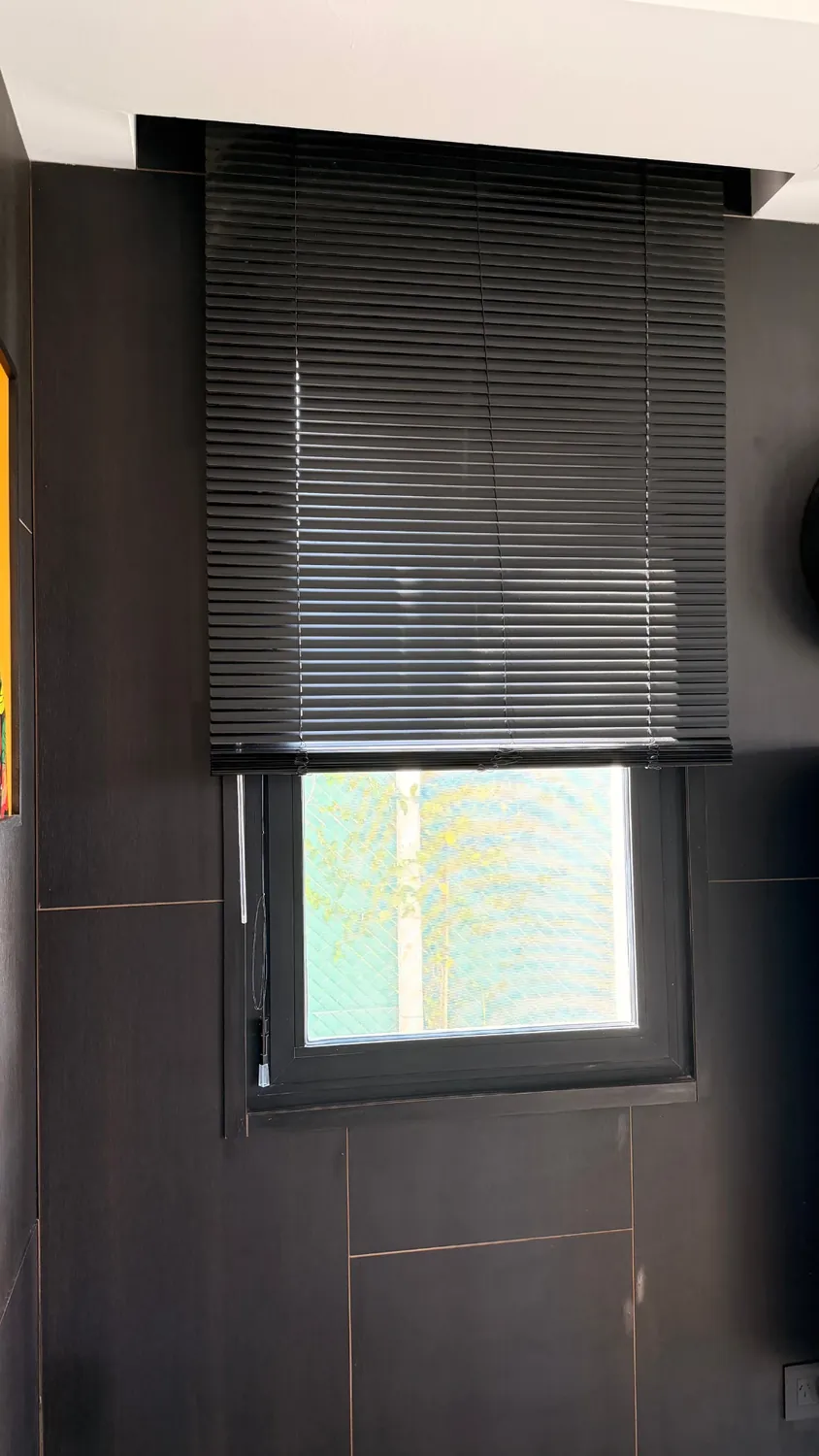 Cortina veneciana de aluminio negra sobre una ventana